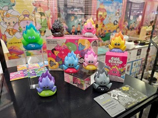 A group of cartoon-style toys displayed on a table, including a book. Fire Friend Blind Box Series by The Jum Thailand available at Strangecat Toys.