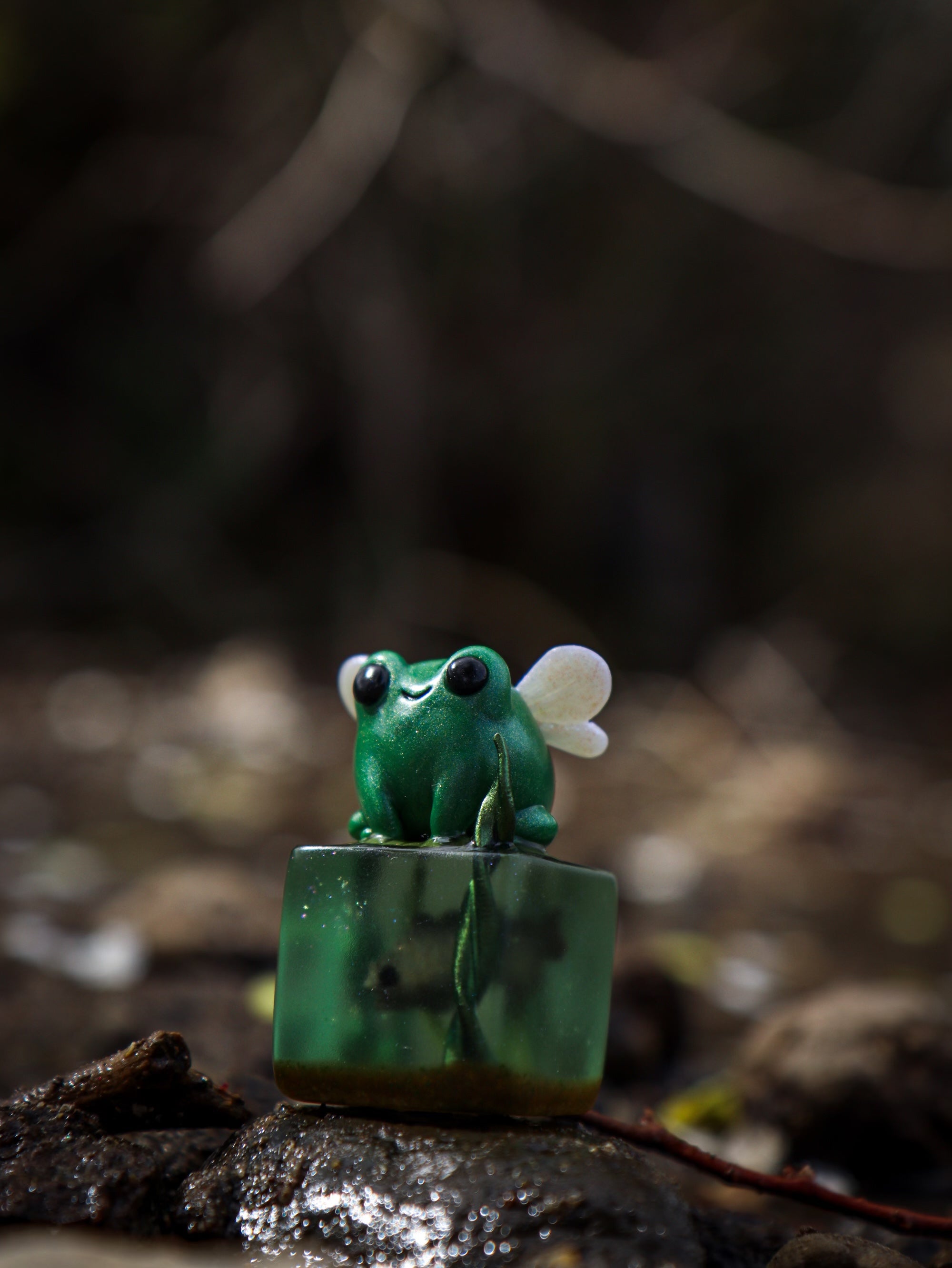 A whimsical green frog sculpture on a cube by Fairies And Fancies, titled Little Shit Big Deal - CUBES. Sculpted by Dr. Polpz. Ships randomly.