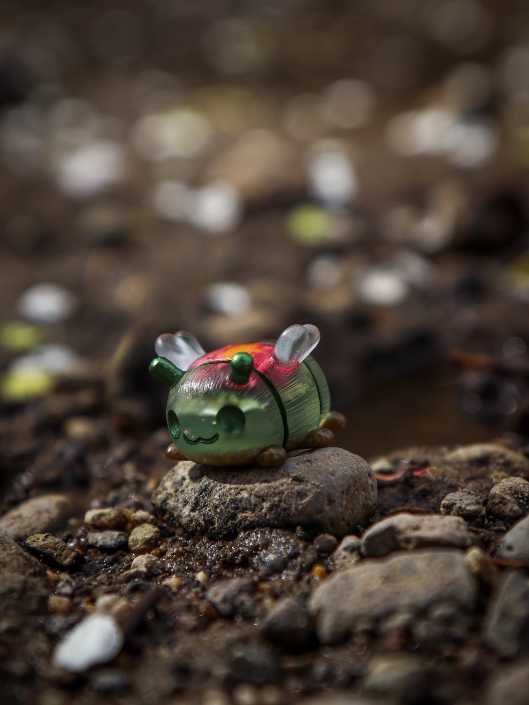 A toy bug on a rock, part of the Little Shit Big Deal - GRUBLETS collection by Fairies And Fancies. Polymer Clay and Resin material, 1 1/2 inches tall.