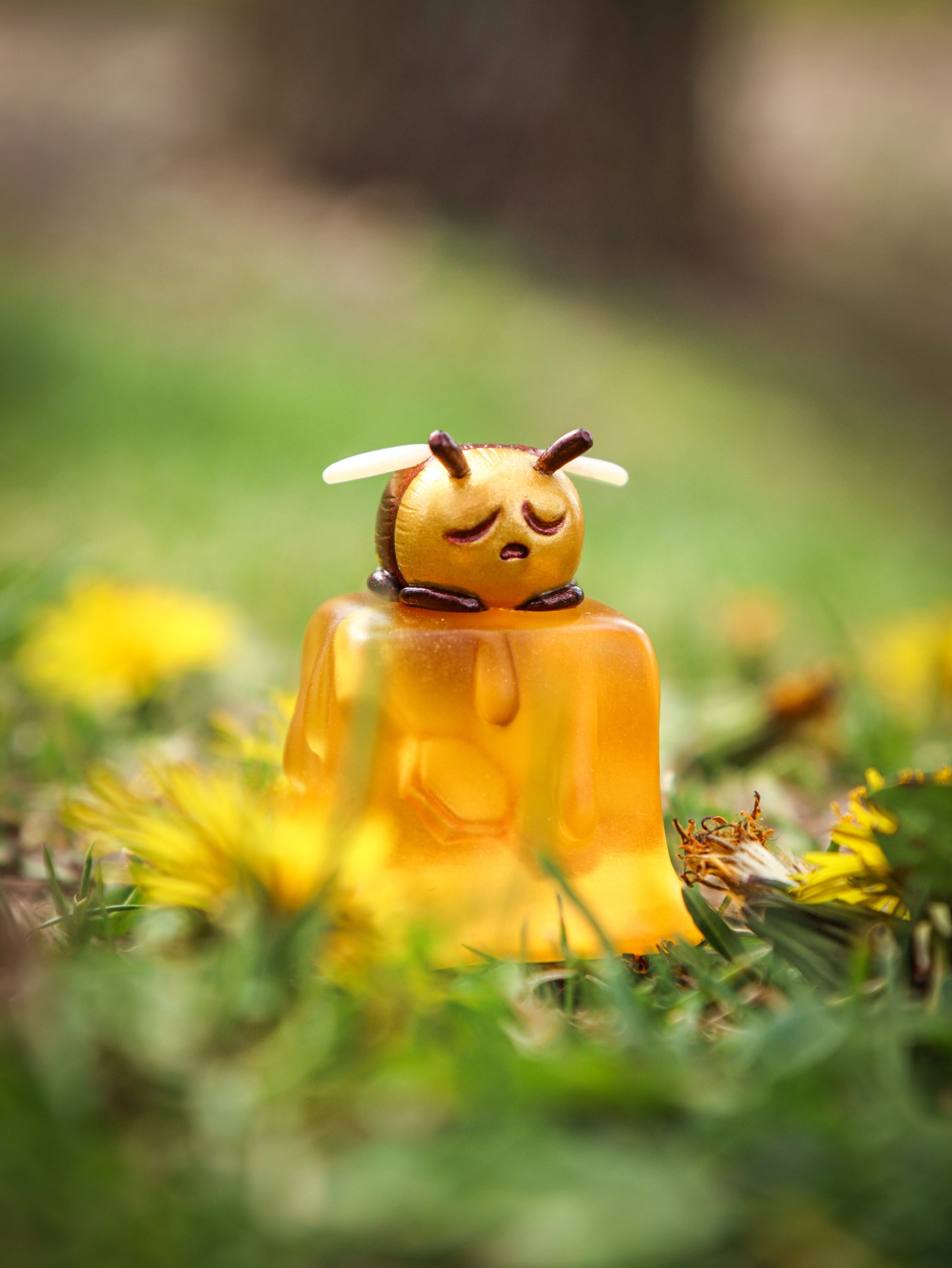 A yellow bee on a cube toy in grass, part of Little Shit Big Deal - CUBES by Fairies And Fancies. Sculpted by Dr. Polpz. A blind box and art toy store.