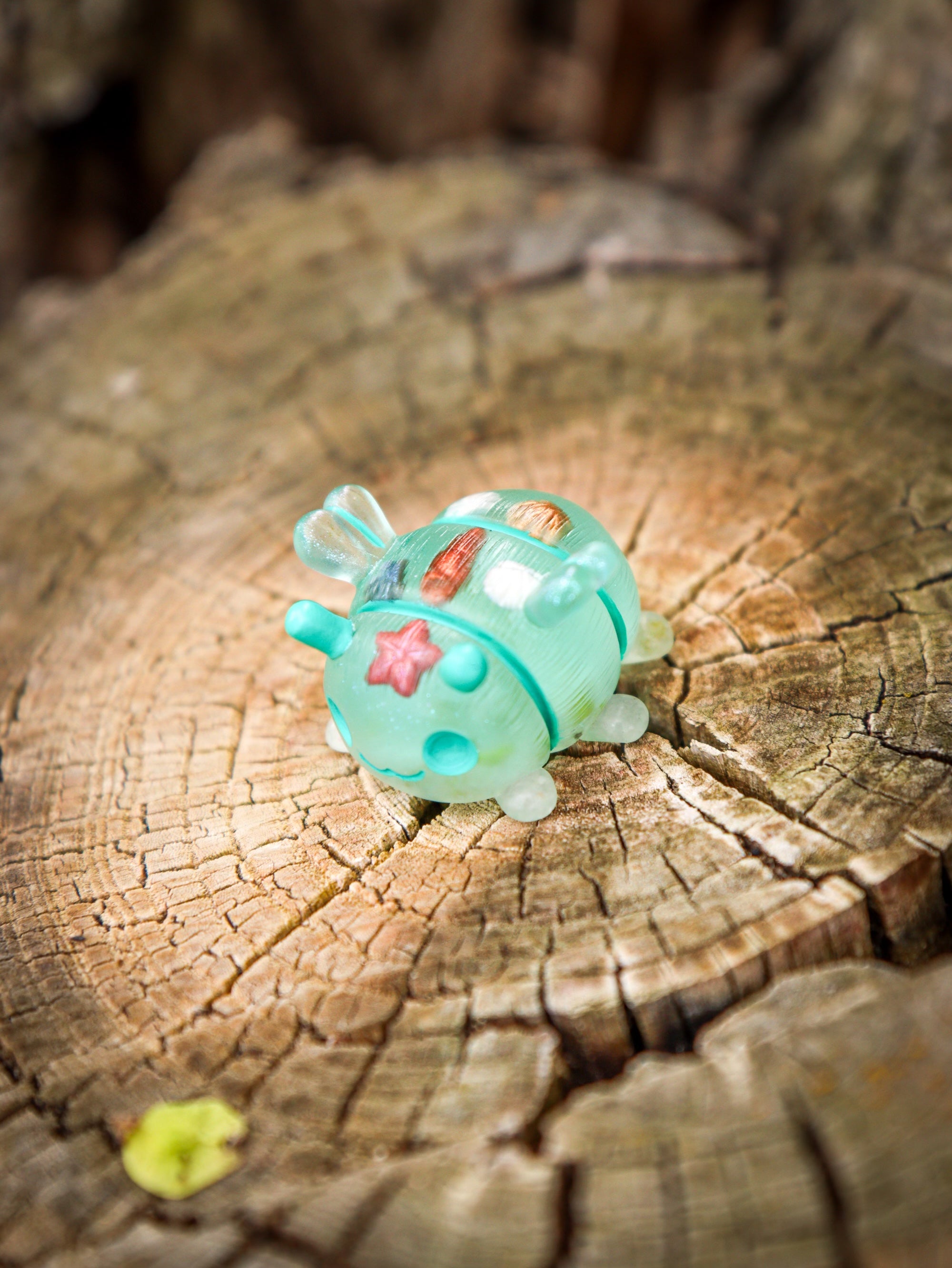 A small toy octopus cube on a tree stump, crafted from polymer clay and resin. Part of the Little Shit Big Deal - GRUBLETS collection by Fairies And Fancies at Strangecat Toys.