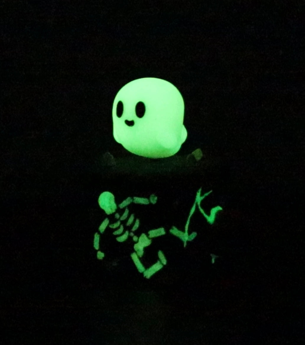 A blind box toy titled Little Shit Big Deal - CUBES by Fairies And Fancies. Glowing green toy with black eyes, skeleton face, and emoticon style. Sculpted by Dr. Polpz.