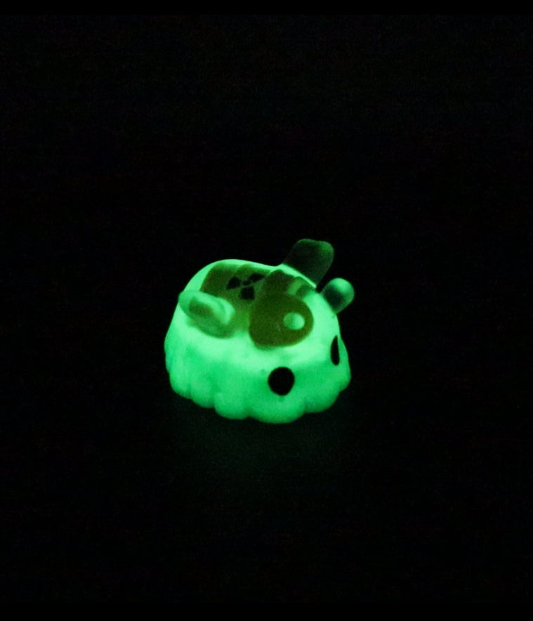A 2-inch tall glow-in-the-dark toy cube featuring a green octopus design made of polymer clay and resin by Fairies And Fancies.