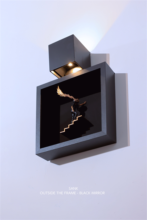 Sank - Outside the Frame: A matte-black shadowbox with a gold-winged figurine on a staircase, featuring built-in downlight. Preorder for Strangecat Toys.