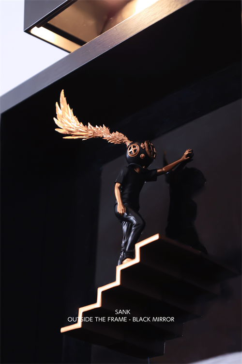 Sculpture: SANK – Outside the Frame, a resin figure with a diving helmet, gold feathers, on a lit staircase. Preorder; ships Q4 2025.