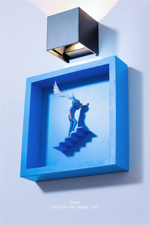 Sank - Outside the Frame: A 3D art piece featuring a blue-clad figure climbing a staircase, enclosed in a sky-blue shadow box.