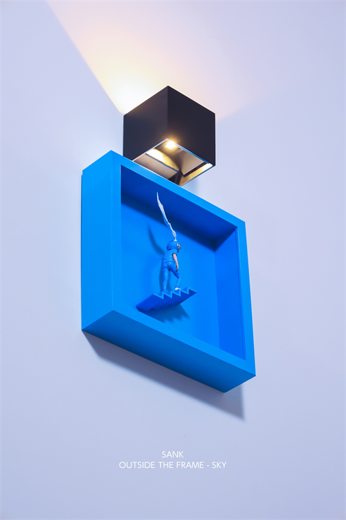 Sank - Outside the Frame: A minimalist art piece featuring a black cube sconce, blue box with a figurine on stairs, and a trailing wisp.