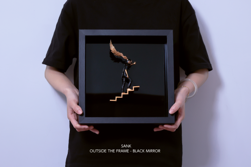 Sank - Outside the Frame: A dark metallic figure with bronze wings climbs golden steps, encased in a black display frame. Preorder, ships end Q4 2025.