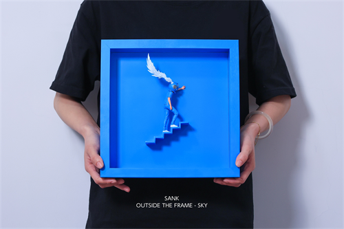 Person holding Sank - Outside the Frame: a blue 3D diorama with a winged figure on steps, in a frame. Preorder for Q4 2025 shipping.