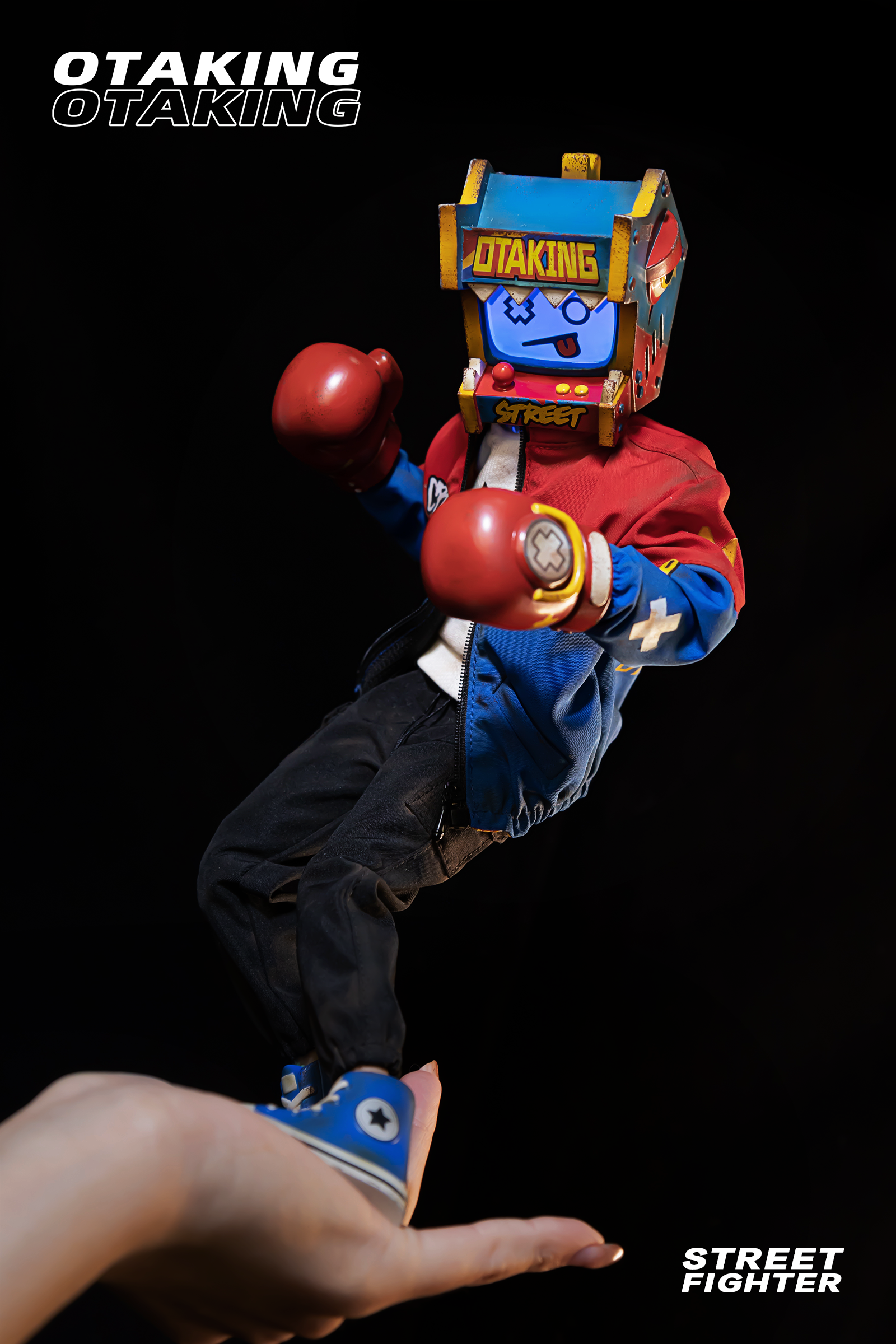 A hand holding a toy machine with a face, a small blue shoe, and a red boxing glove in the OTAKING - Street Fighter collection.
