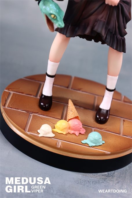 Medusa Girl-Green Viper figure on brick base, featuring pleated skirt, Mary-Jane shoes, and snake accessory, with spilled pastel ice-cream. Preorder collectible by Yoshioka.