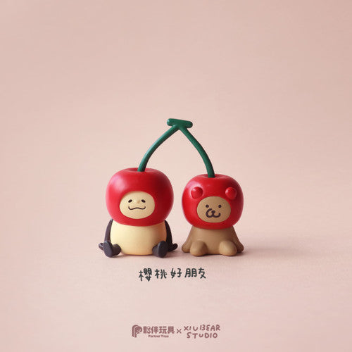 Two figurines with cherry helmets from the Yum Yum Time Blind Box Series: a pale figure and a brown puppy, labeled “Cherry Good Friends.”