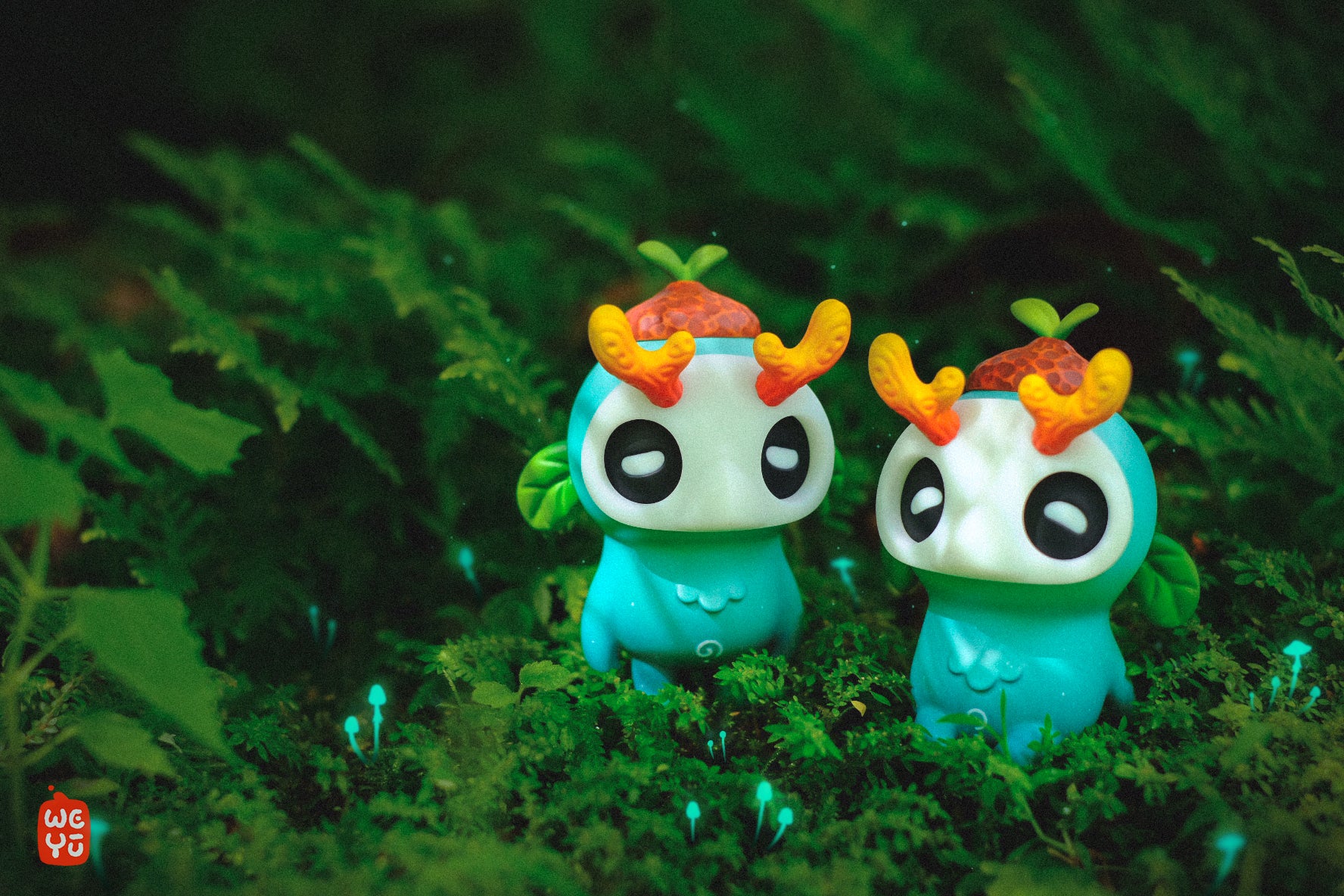 Ori Muffinn: The forest spirit figurines by Madkids on moss, featuring turquoise bodies, mask-like faces, orange horns, and glowing mushrooms in a whimsical diorama.