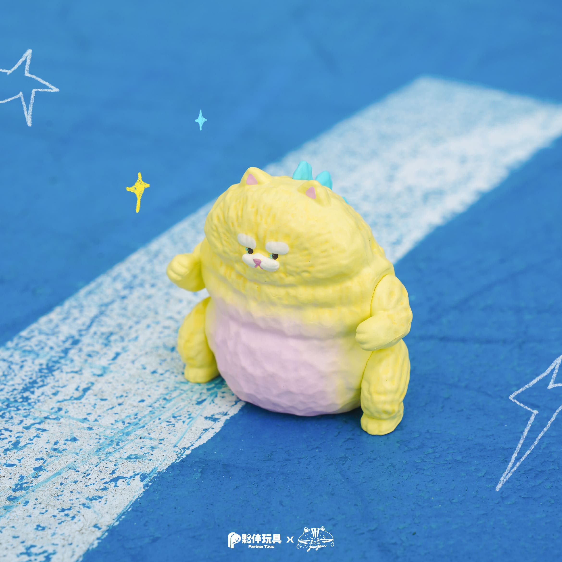 HanHanzoo - HanHan Dragon Blind Box toy figure, pastel-yellow with kitty features and turquoise spikes, sitting on a blue and white surface with doodled stars.