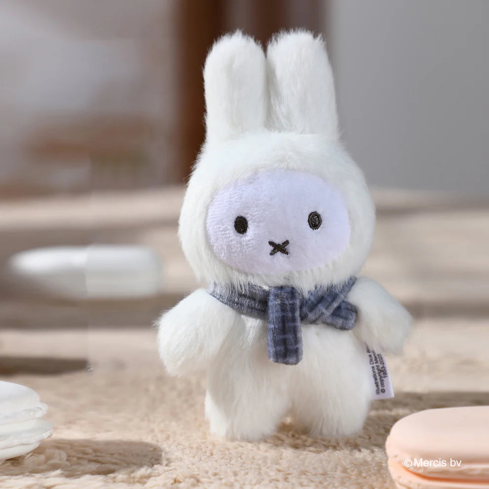Miffy Macaron V2 Plush Keychain Blindbox features a white plush bunny with a checked scarf, standing on a soft surface with pastel macarons nearby.