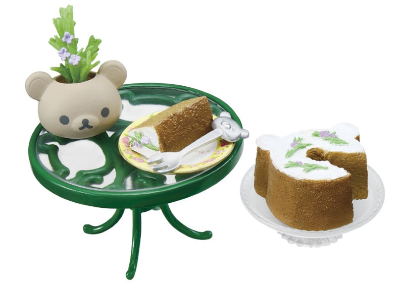 Rilakkuma Longing British Tea Time Re-ment Blind Box Series displayed with a cake, teddy bear, and spoon on a small table.
