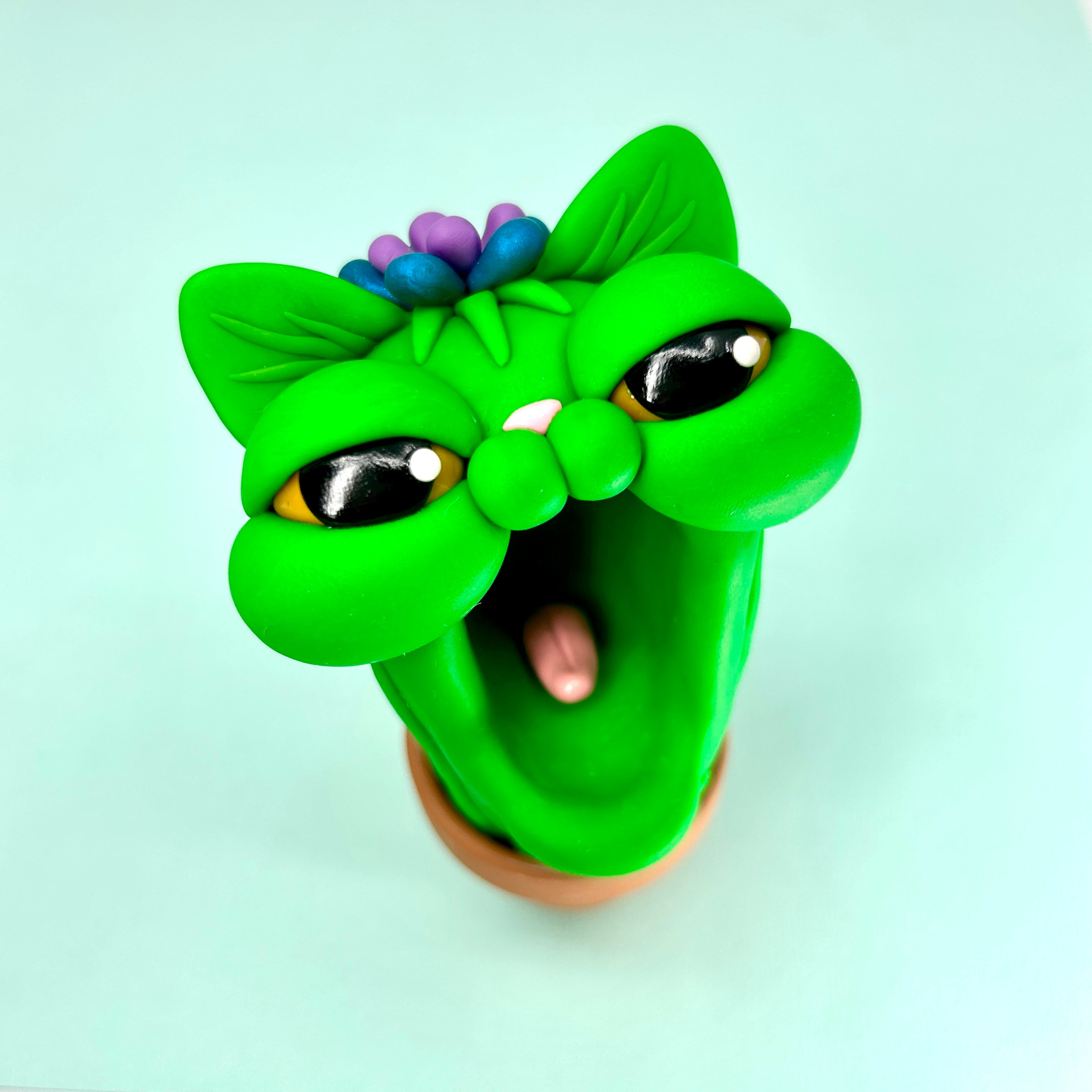 Polymer clay toy of green cat head with mouth open, part of Simon Says Macy & Friends collection.