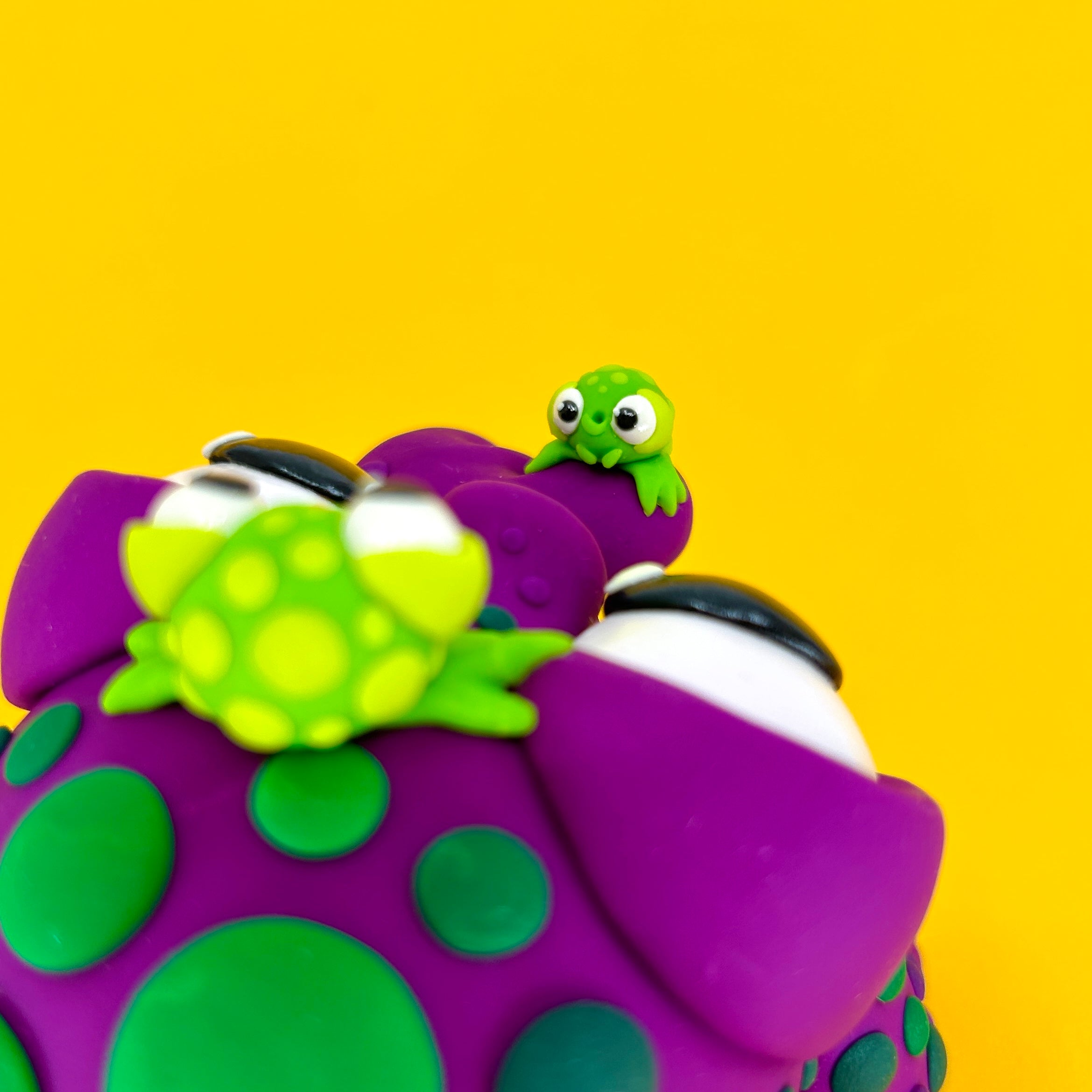 Close-up of a toy frog from Simon Says Macy & Friends - IT'S STICKY! surrounded by cake decorating supplies.
