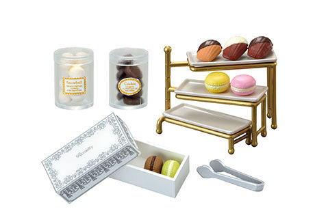 Chocolaterie Re-ment Blind Box Series featuring a miniature dessert set with jars, a tiered stand of macarons, chocolates, and a decorative box with tongs.