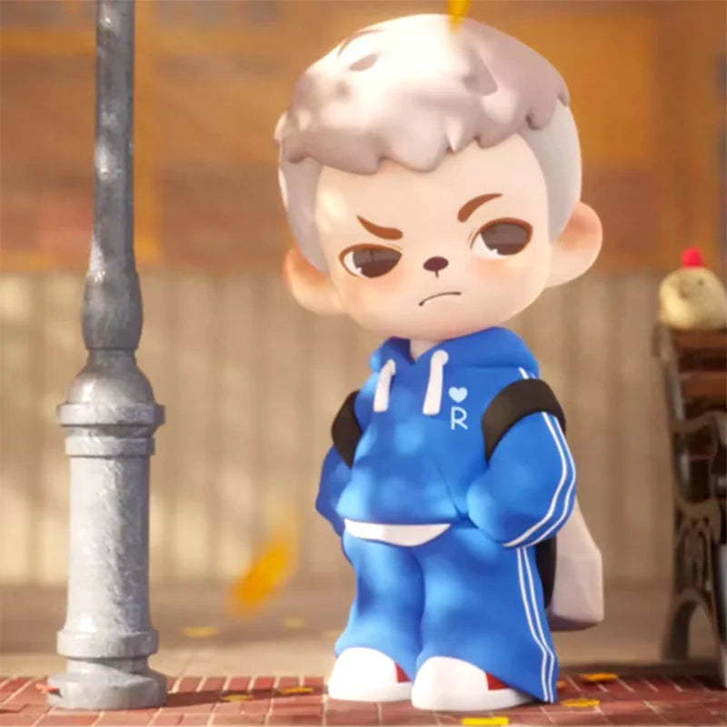 Boy Rayan Youth Days Series 2 Blind Box: 3D cartoon character in blue tracksuit with R emblem, backpack, on brick sidewalk under lamppost, autumn leaves falling.
