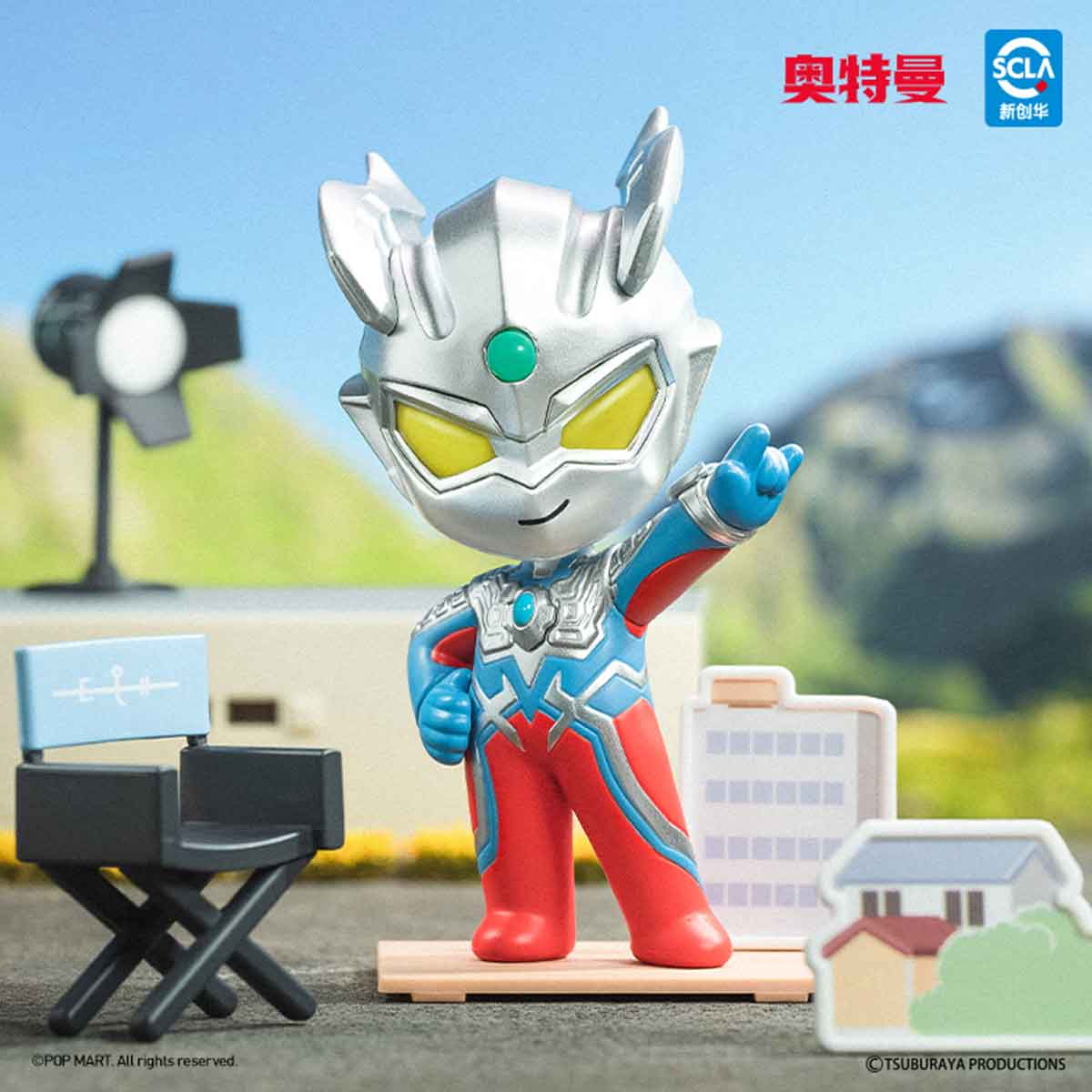 Ultraman Shooting Studio Series Figure in classic suit, posed on a wooden platform with diorama elements like a director’s chair and model buildings, waving.