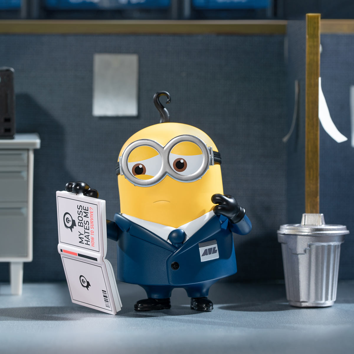 Toy figurine of a yellow cartoon character holding a book from the Universal Despicable Me 4 Blind Box Series. Preorder available, ships late July 2024.