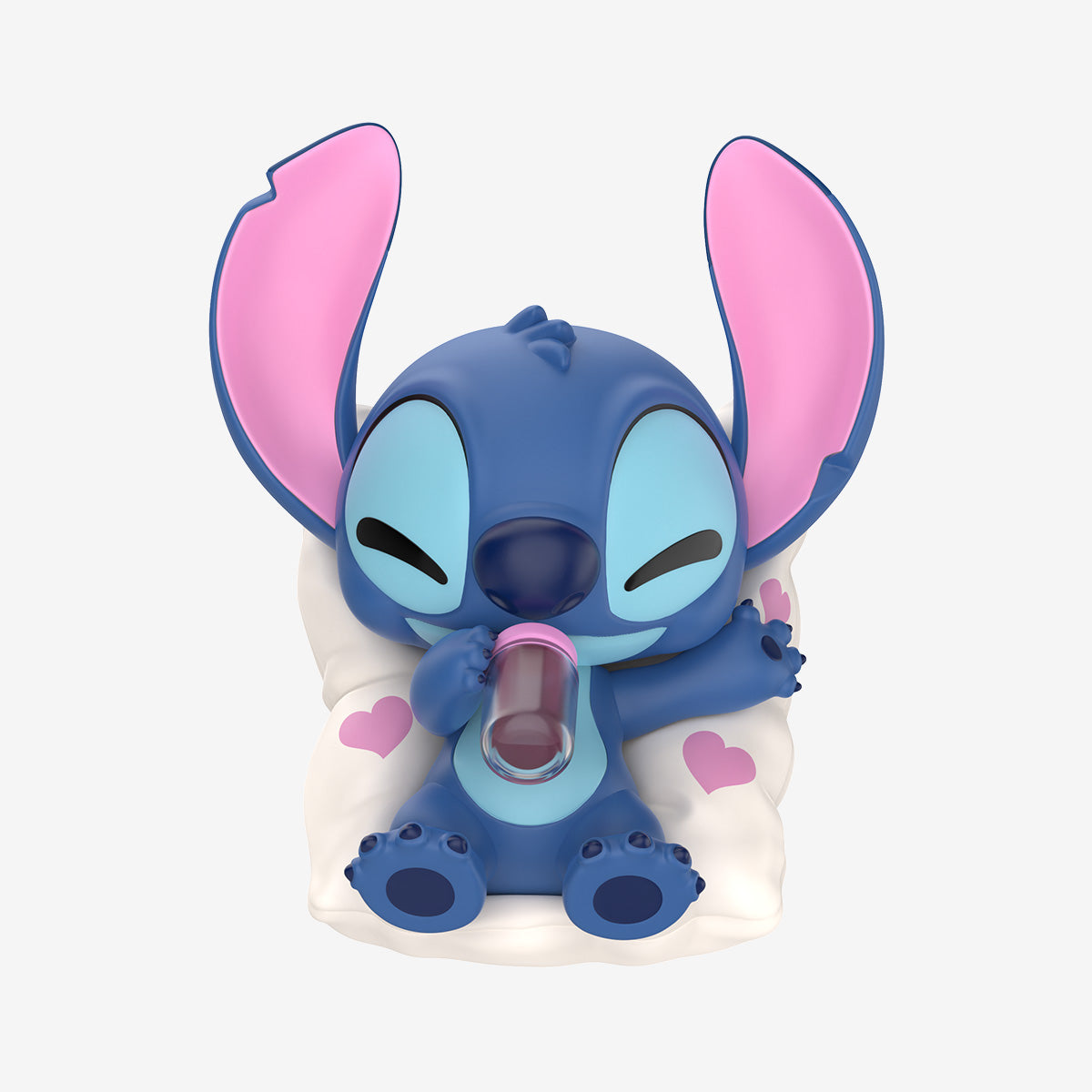 Disney Stitch on a Date Series figure, a baby Stitch sipping contently on a bottle, seated on a pillow with pink hearts. Preorder for Oct 2025.