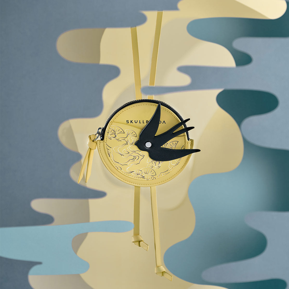 SKULLPANDA The Mirage Series Mini Bag featuring a black bird design on a compact yellow clock-shaped structure, made of PU with adjustable lanyard.