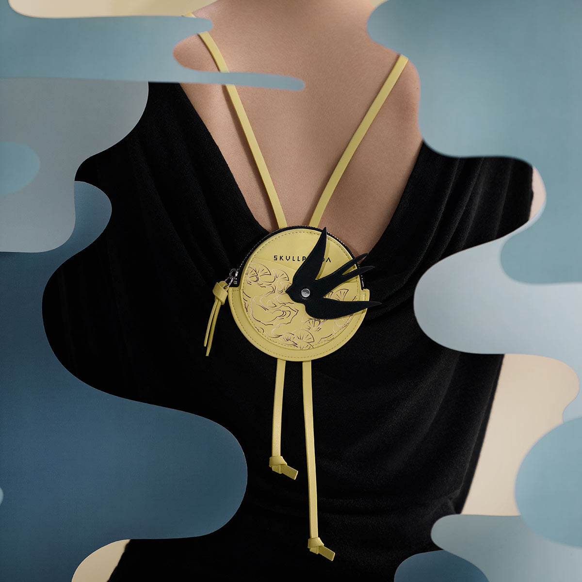 SKULLPANDA The Mirage Series Mini Bag, featuring a unique black bird design on a yellow round surface, adjustable lanyard, and compact PU shell.