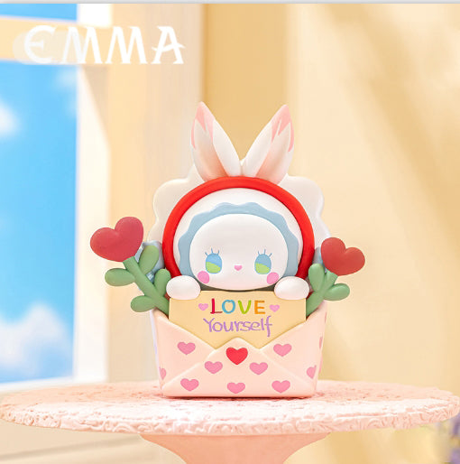 Emma Dopamine of Love Blind Box figurine, featuring a bunny-eared character with a LOVE Yourself card, nestled in a heart-patterned box on a pink pedestal.