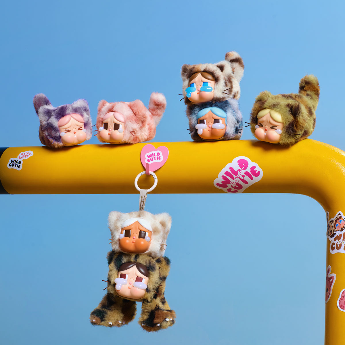 CRYBABY Wild but Cutie Series - Vinyl Plush Pendant Blind Box features plush cat figures with human-like faces, teardrops, and keychain attachments, displayed on a decorated yellow bar.