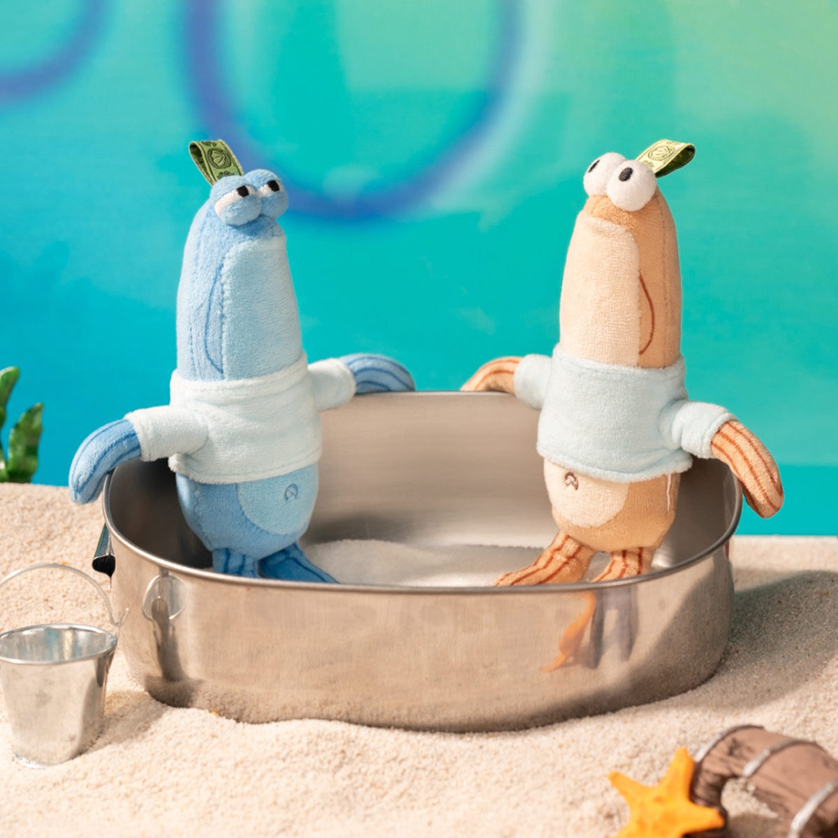 Bikini Bottom Buddies - Whimsical Plush toys in a sandy tray, featuring googly eyes and fabric tags, set in a playful beach-themed display.