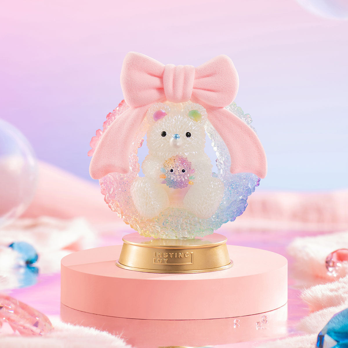 INSTINCTOY Muckey Celebration gift Series Figure: a translucent bear with sparkly resin, holding a spiky creature, inside a rainbow ring with a pink bow.