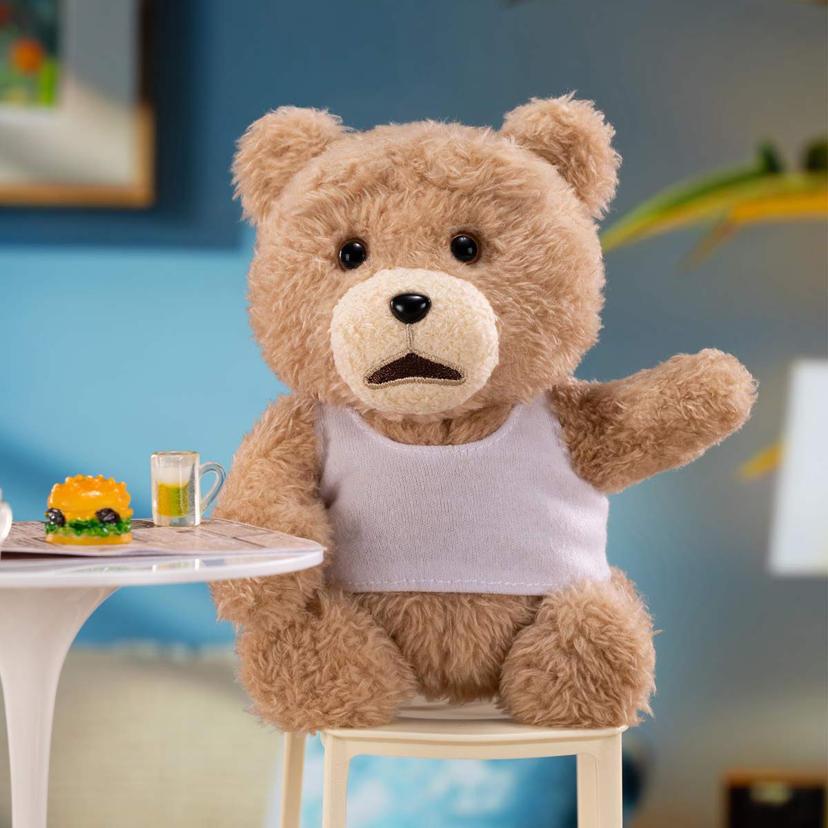 Ted2 Teddy Bear Action Plush Pendant seated with a mini cheeseburger and drink on a table, wearing a white shirt. Preorder for November 2025 release.