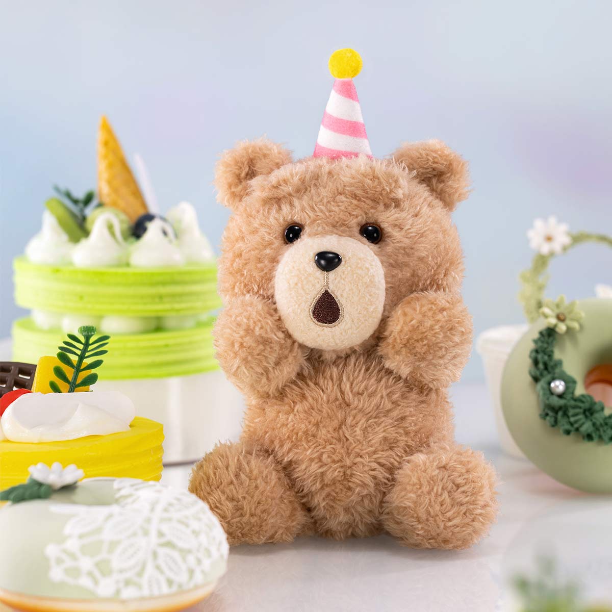 Ted2 Teddy Bear Action Plush Pendant sits festively with desserts, wearing a striped party hat, part of a collectible series available for preorder.