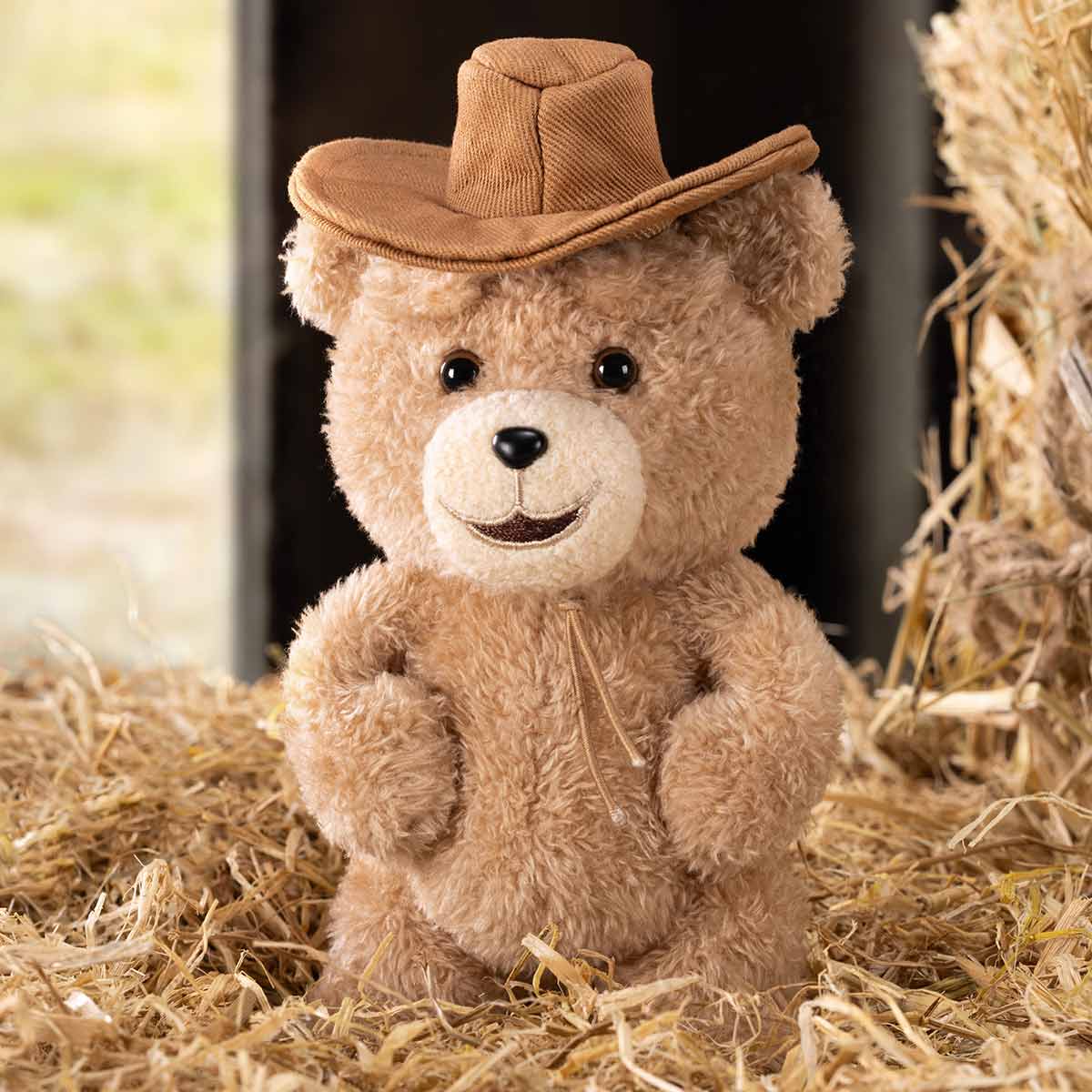 Ted2 Teddy Bear Action Plush Pendant wearing a cowboy hat, posed amid straw, embodies a rustic charm. Part of a collectible series from Strangecat Toys.
