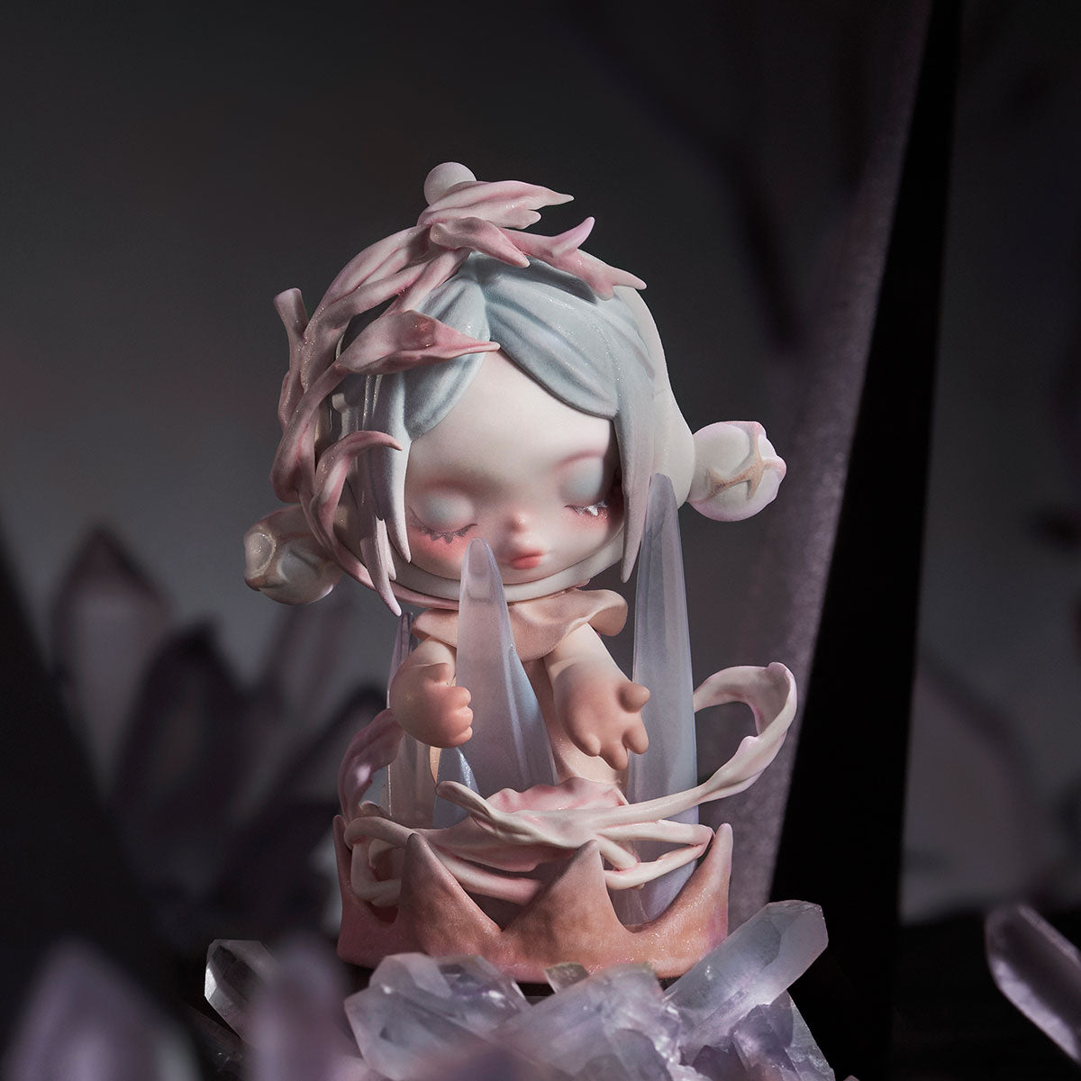 SKULLPANDA The Paradox Series Figure: A childlike figurine with pastel hair, seated among crystal shards in a dimly lit scene, available for preorder at Strangecat Toys.