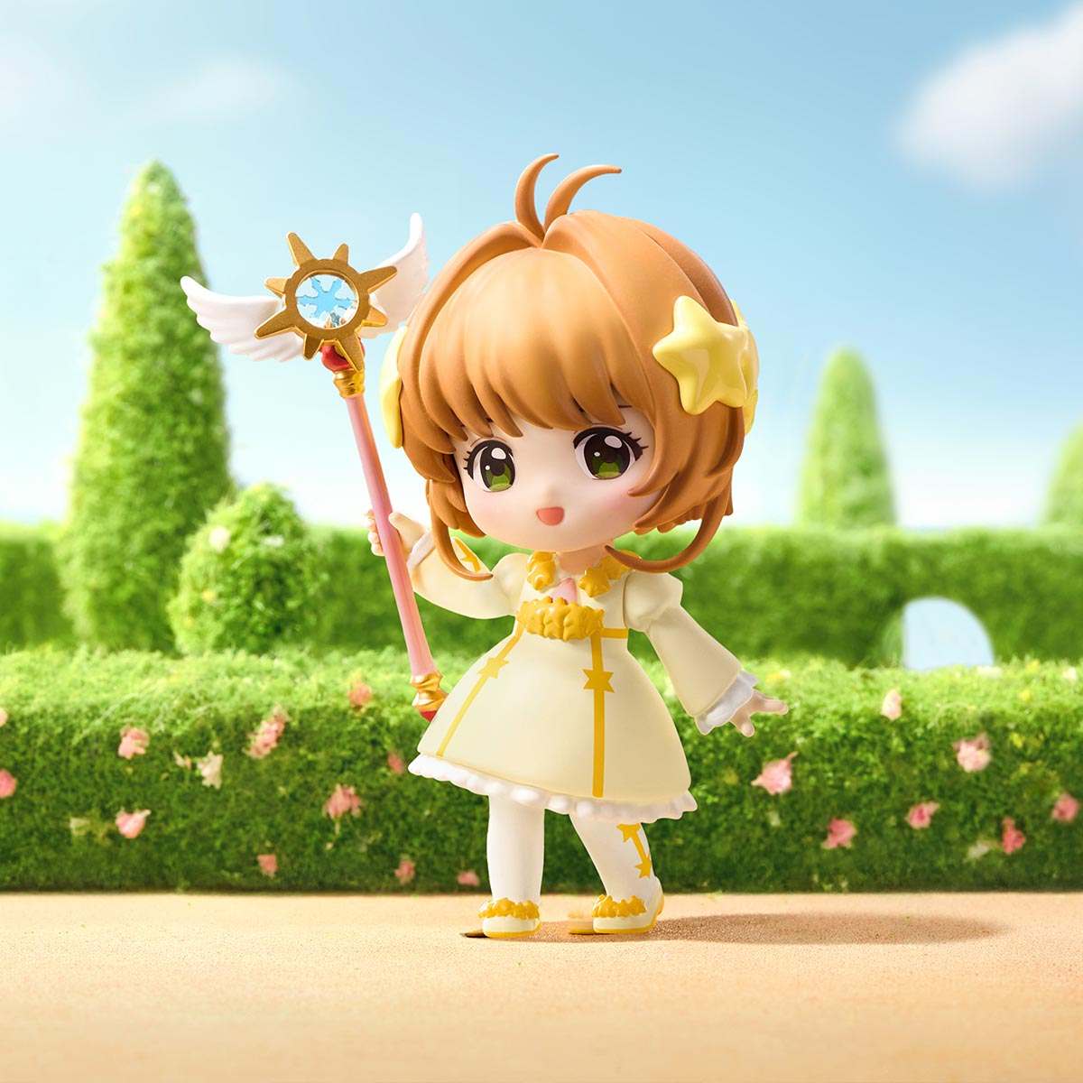Cardcaptor Sakura: Clear Card Series Figures - Preorder featuring a chibi girl with magical staff, cheerful expression, and star motifs against a hedge backdrop.