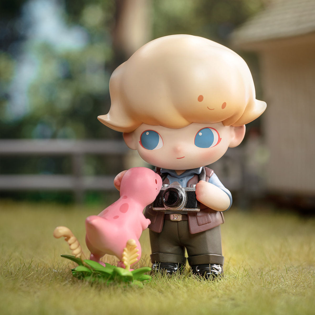 DIMOO Jurassic World Series figurine: chibi blond boy with camera and pink dinosaur toy. Preorder for Strangecat Toys' blind box art collection.
