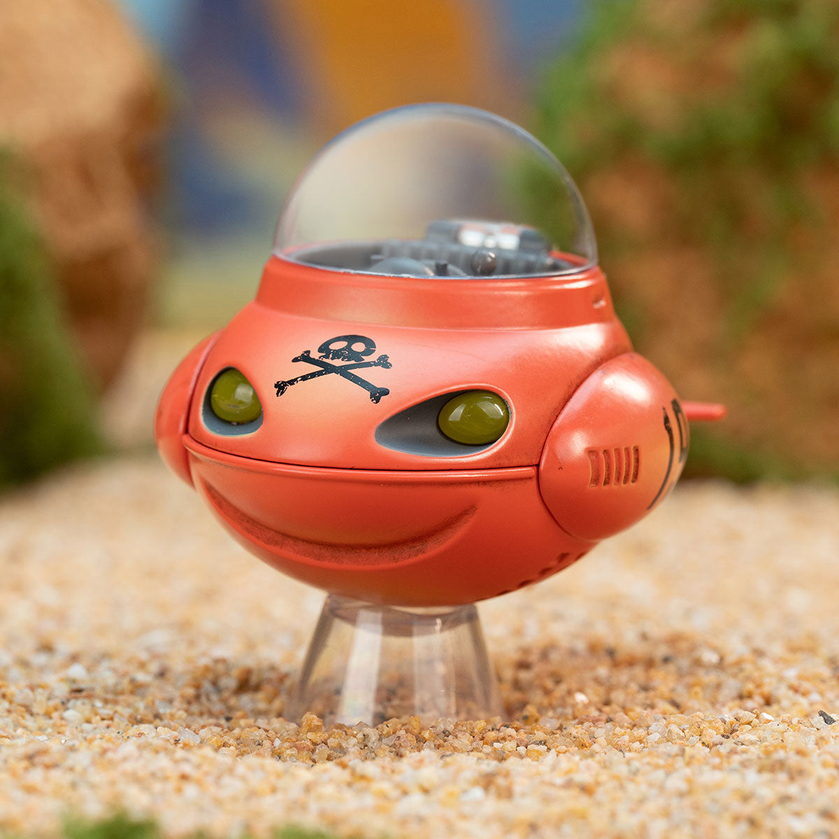 DRAGON BALL-Alloy Vehicles Series Figure: A red toy vehicle with a pirate motif, featuring a bubble cockpit and green eyes, displayed on a sandy diorama stand.