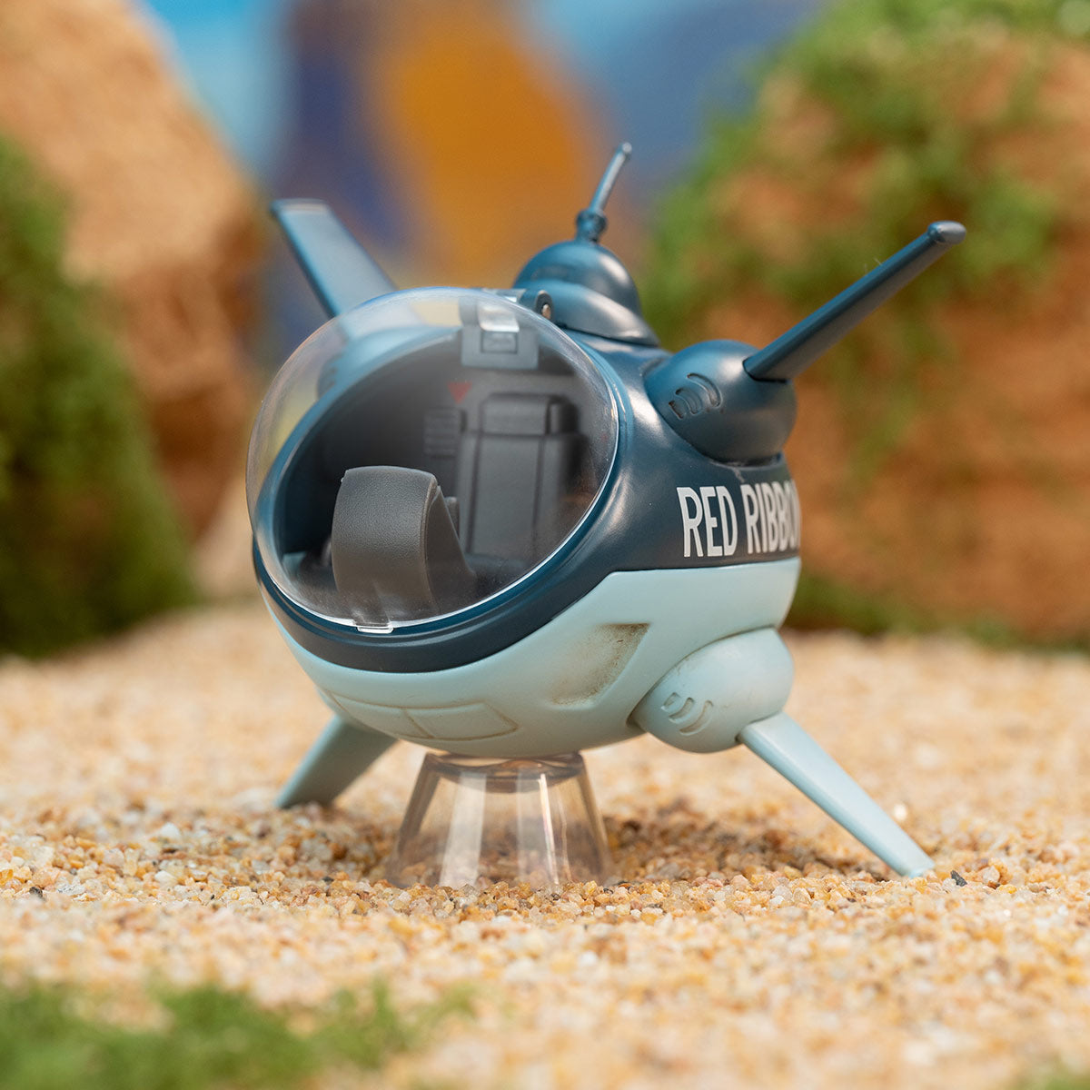 DRAGON BALL-Alloy Vehicles Series Figures: A blue mini-shuttle with RED RIBBON, clear canopy, landing legs, on sandy surface. Preorder for October 2025.