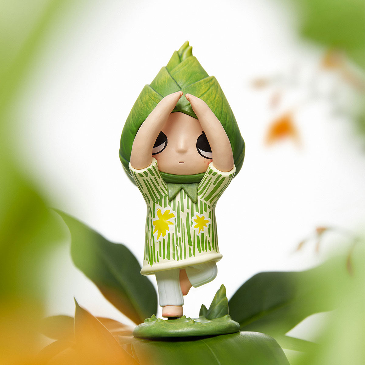 Nyota I Am the Seasons Series Figure in a leaf hood and floral tunic, posed in a yoga tree pose, available for preorder.