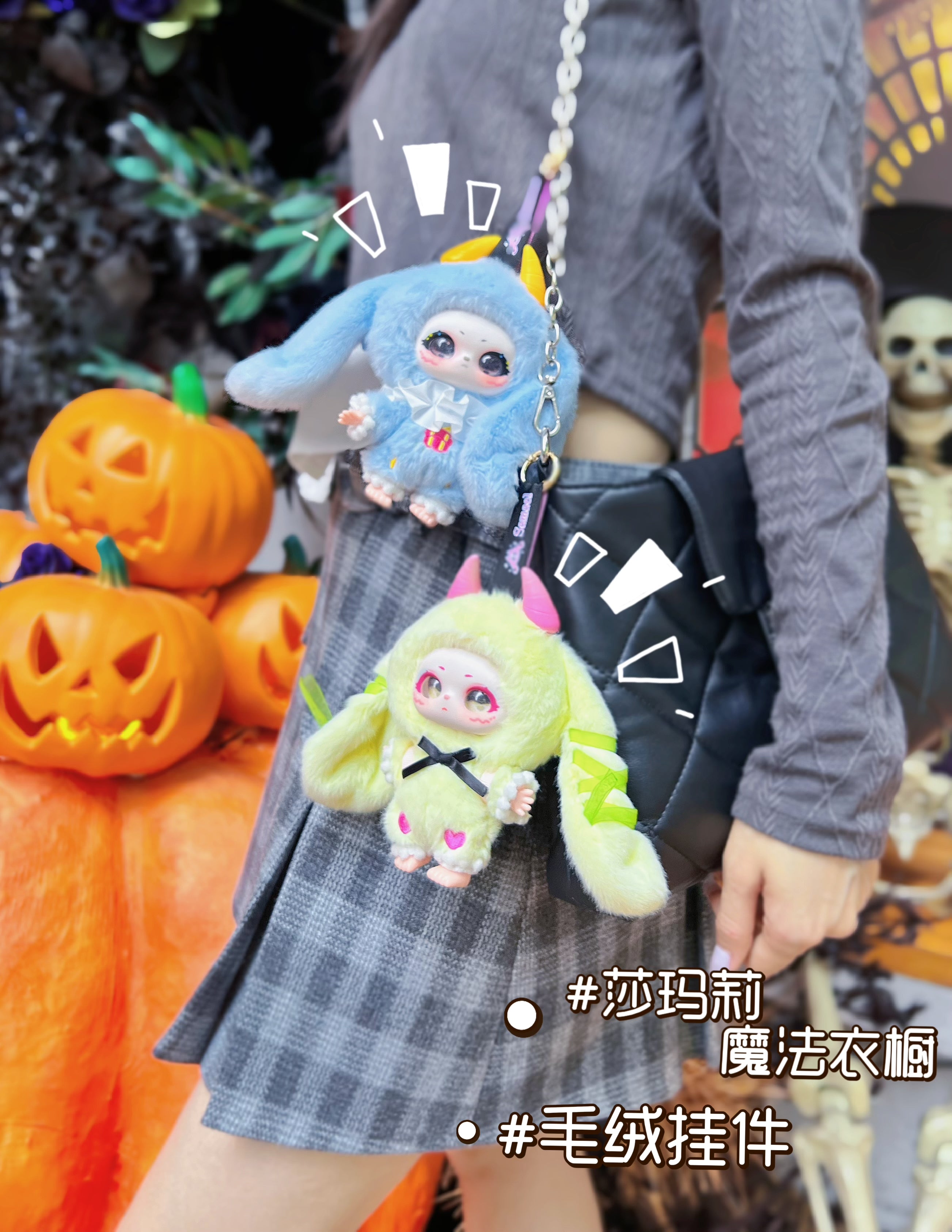 Person with grey outfit holding a black bag adorned with Baby Three - Shamali Magic Wardrobe plush-doll key-chains in bunny and lime-green costumes.