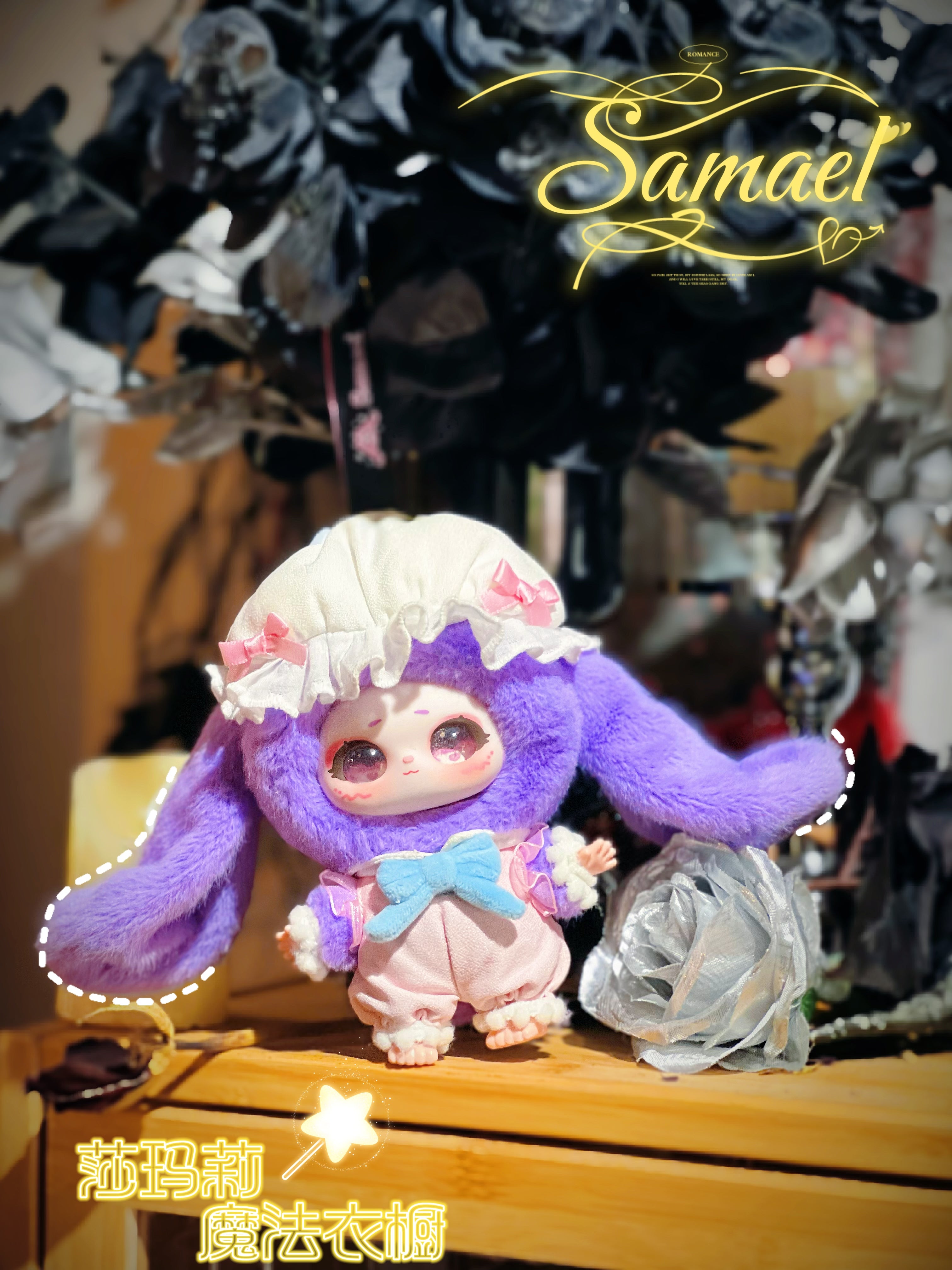 Baby Three figurine from Shamali Magic Wardrobe, featuring a purple bunny-ear hood and pink romper with a blue bow, posed beside a silvery fabric rose.