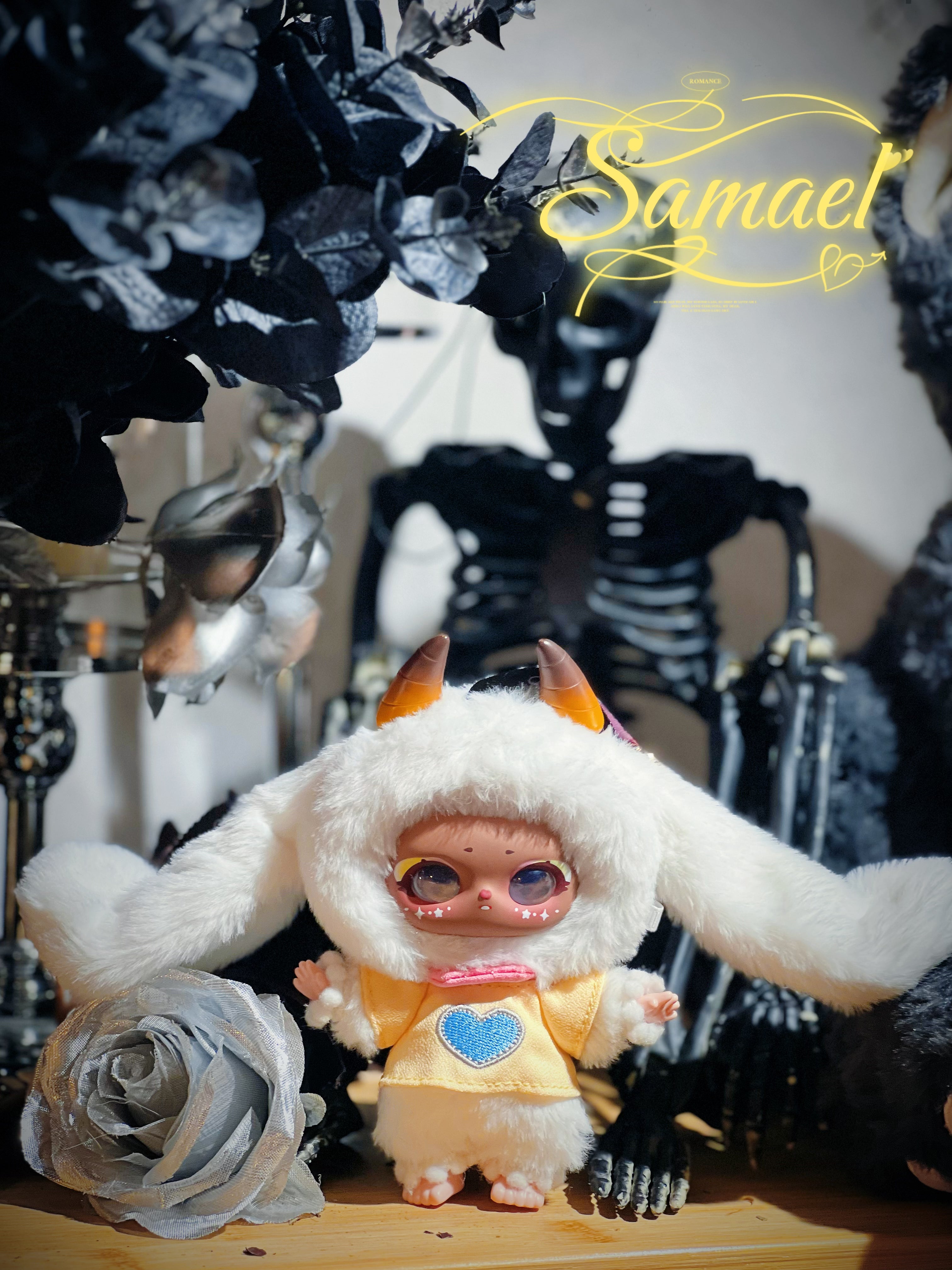Baby Three - Shamali Magic Wardrobe collectible doll in a fluffy suit with rabbit ears, orange horns, and a yellow tunic, beside a grey rose and skeleton prop.