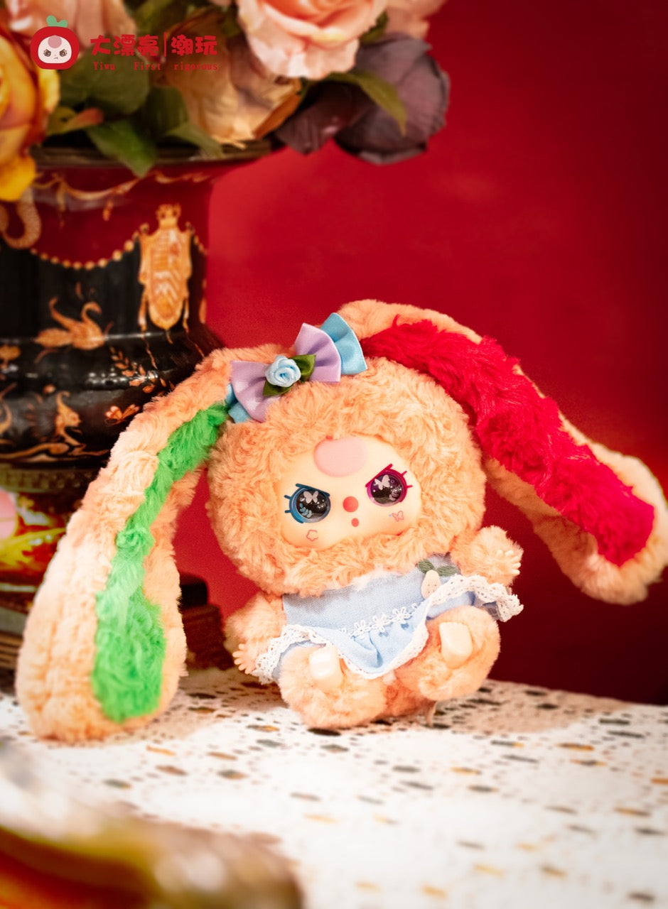 Baby Three - Lily Rabbit Town 4 plush toy with floppy ears, a lace-trimmed blue dress, and decorative bow, seated near flowers. Preorder available.