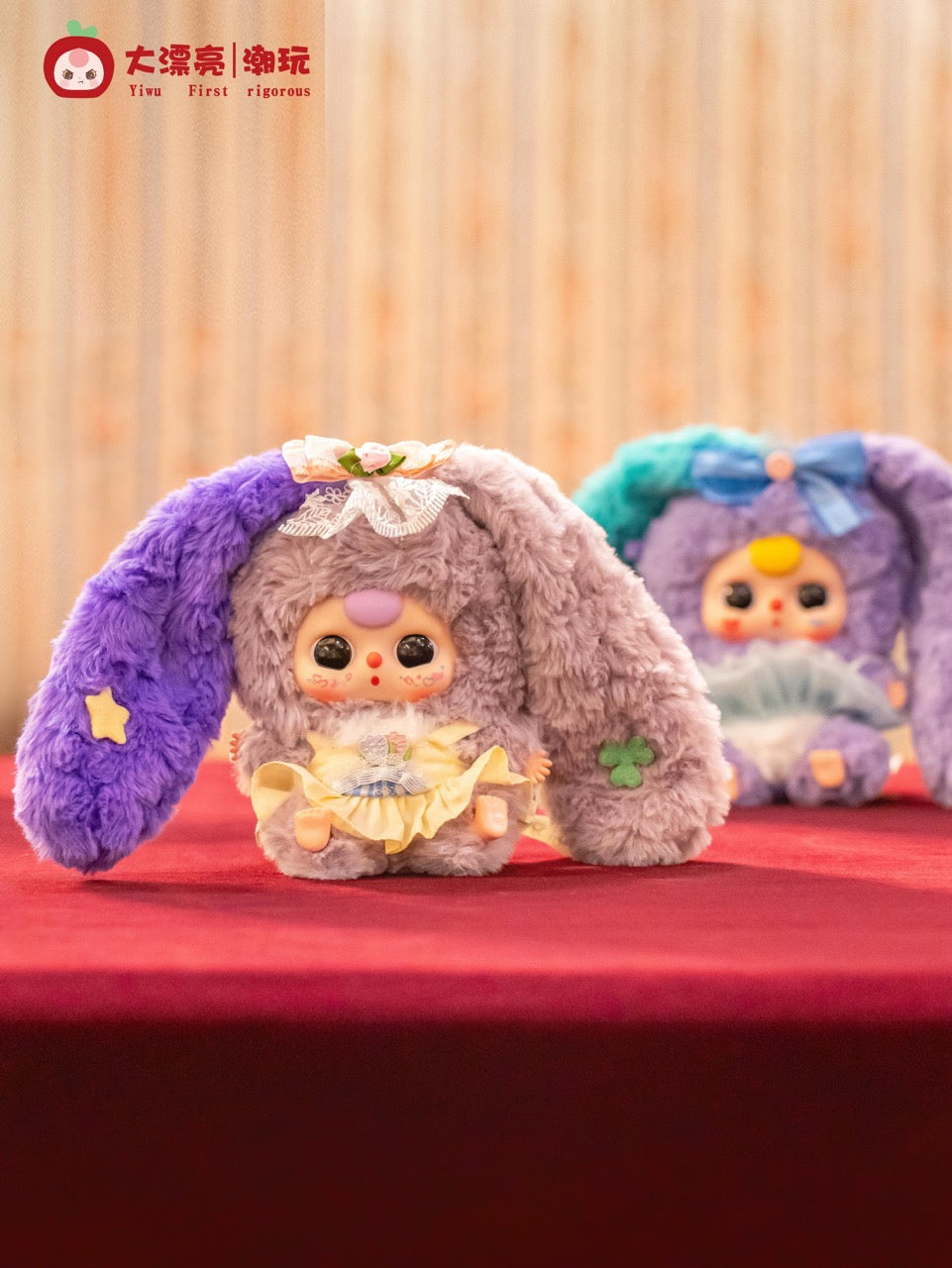 Two Baby Three - Lily Rabbit Town 4 plush dolls with floppy ears and frilly outfits, posed on a red cloth.