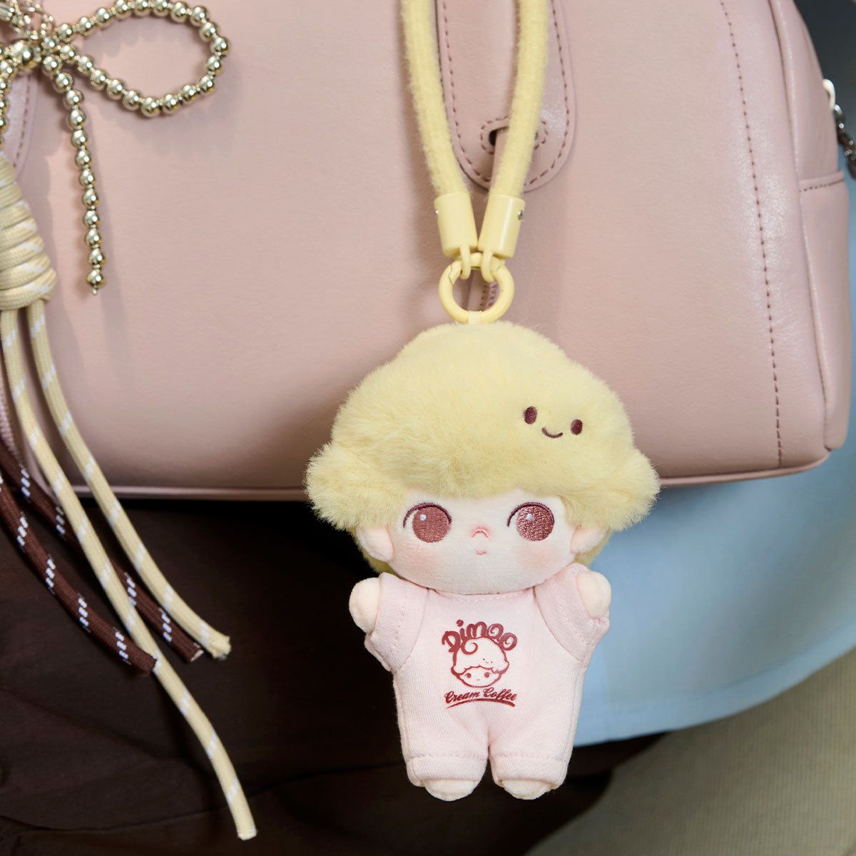 Dimoo Crush on Coffee Series plush keychain clipped to a handbag, featuring a cute face, yellow hair, and pink romper with Cream Coffee logo.
