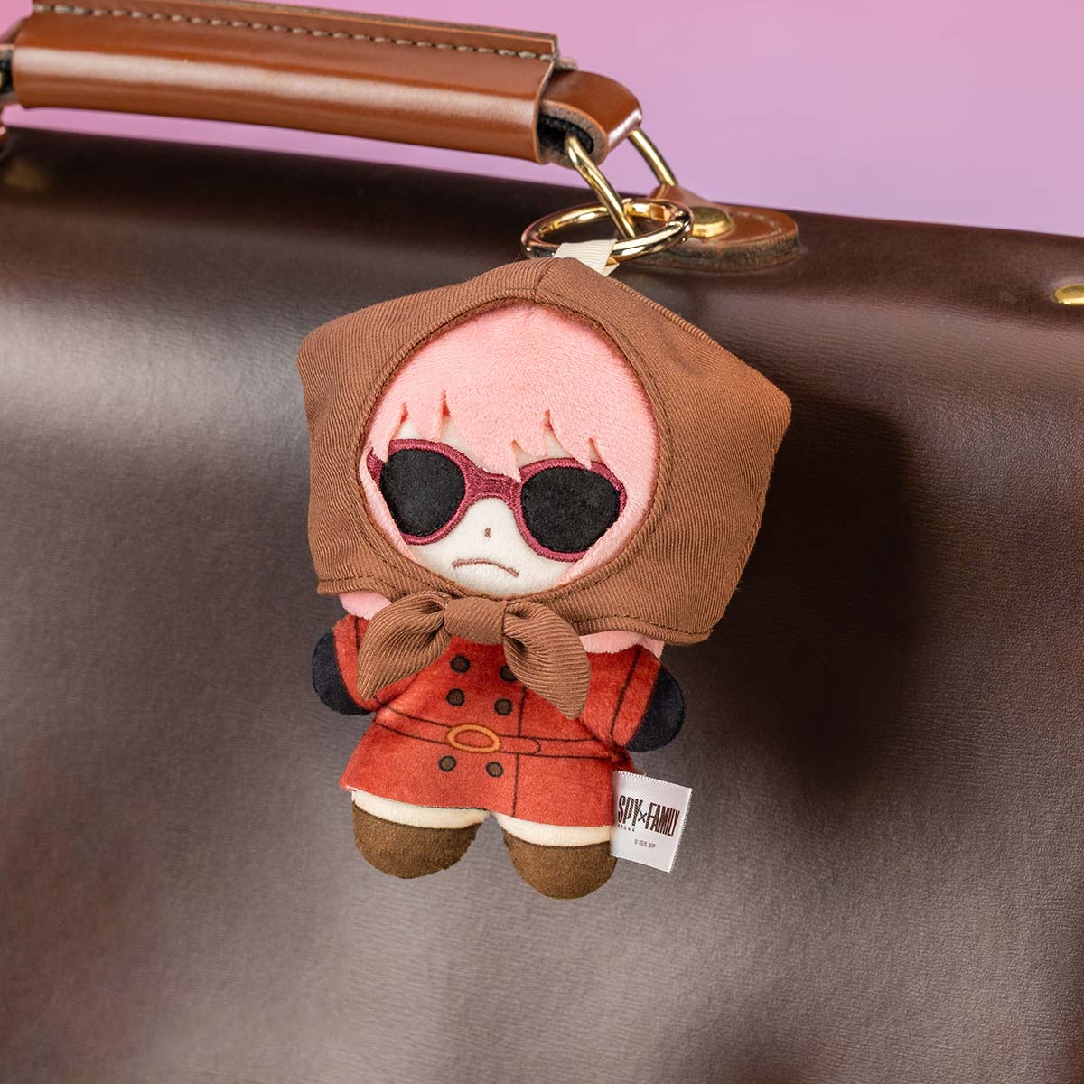 SPY × FAMILY Character Series Plush Blind Box featuring Anya Forger charm in stylish attire, hanging from a gold key-ring on a leather bag.