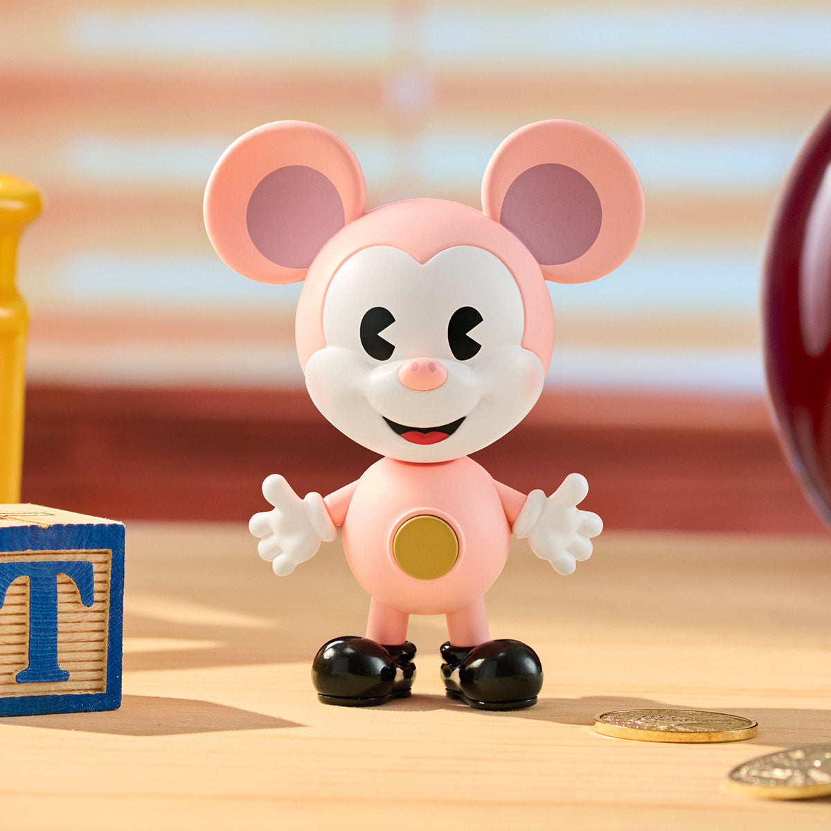 Disney Mickey Remixed: Mickey Meets Pixar Series Figures - Preorder. Pink vinyl-style mouse figurine with white face, gold button, and black shoes, flanked by a blue T block and coins.